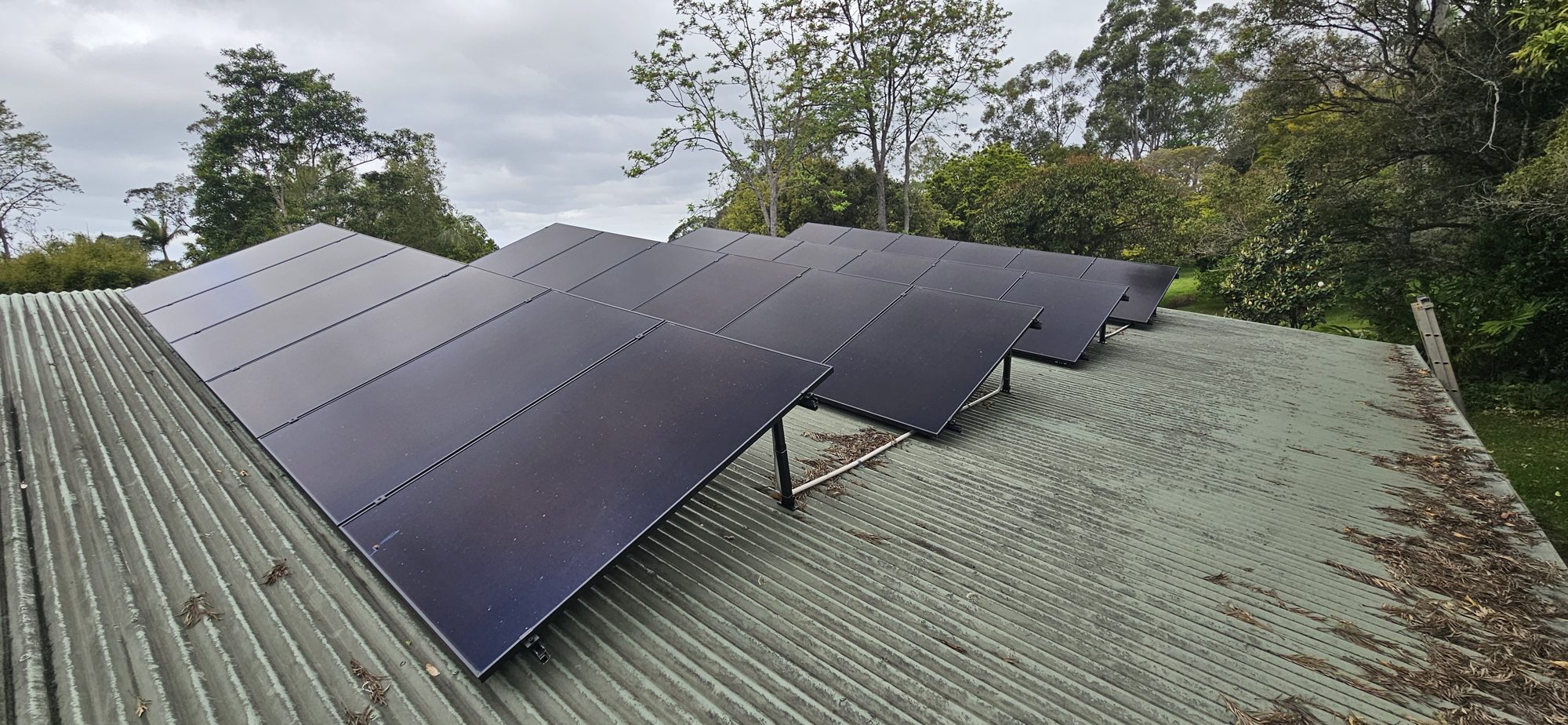 Rows of black AIKO Neostar solar panels on a green metal roof in the Mullumbimby hinterland, installed by Sun Connect Solar