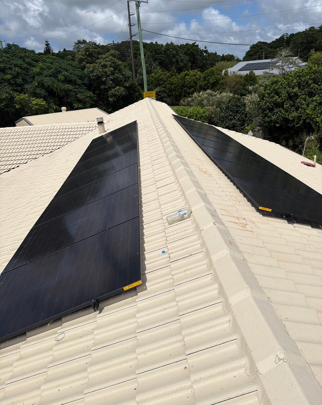 All-black Jinko solar panels along a cream tile roof with trees behind in Alstonville All-black Jinko solar panels along a cream tile roof with trees behind in Alstonville, installed by Sun Connect Solar