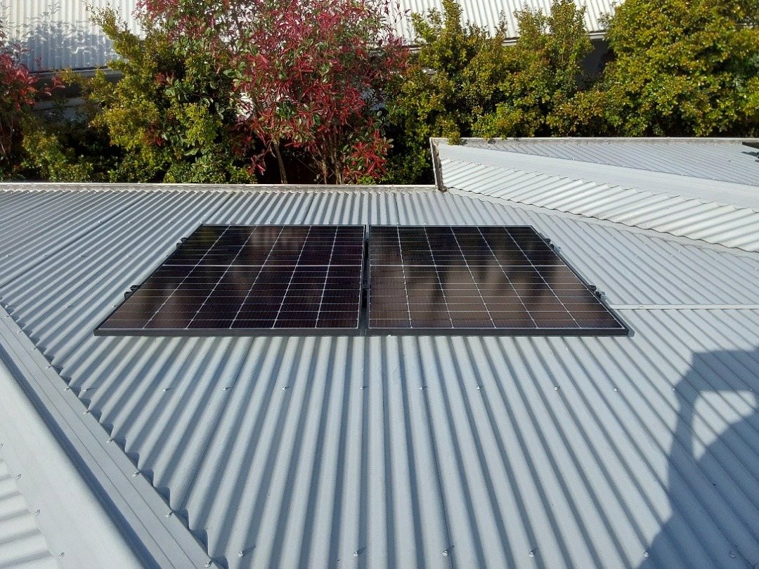 Two Seraphim solar panels on a small metal roof section above a garden in Bangalow, installed by Sun Connect Solar