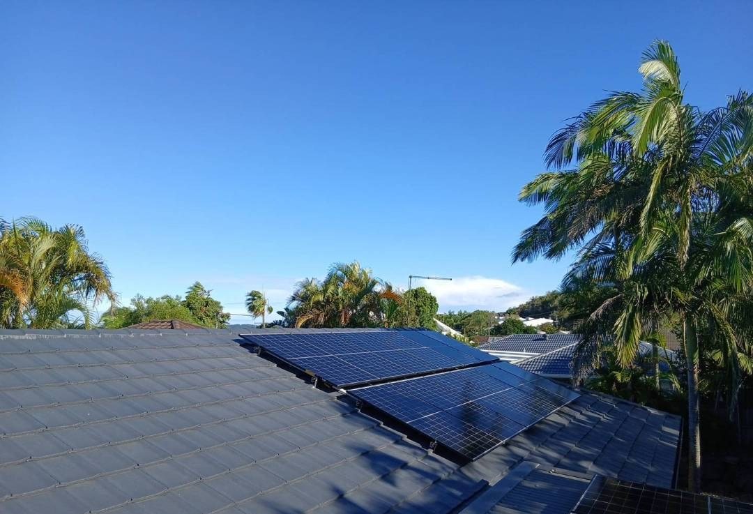 AIKO solar panels on a tiled roof in Byron Bay with palm trees and blue sky AIKO solar panels on a tiled roof in Byron Bay with palm trees and blue sky, installed by Sun Connect Solar