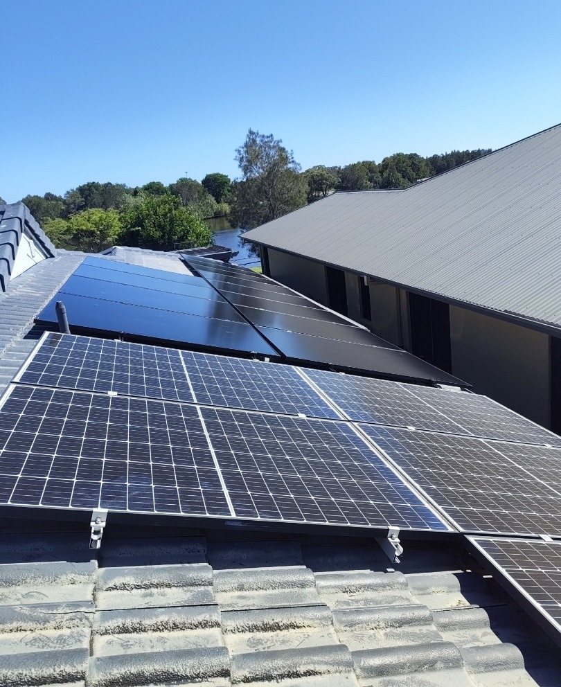 All-black AIKO solar panels on the upper face of a tiled roof in East Ballina All-black AIKO solar panels on the upper face of a tiled roof in East Ballina, with water and trees behind, installed by Sun Connect Solar