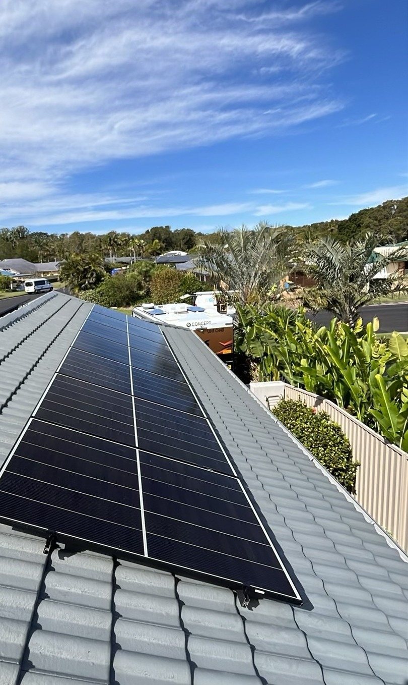 Jinko Tiger Neo III solar panels in a long block on a grey tile roof in East Ballina Jinko Tiger Neo III solar panels in a long block on a grey tile roof in East Ballina, with palms and homes behind, installed by Sun Connect Solar