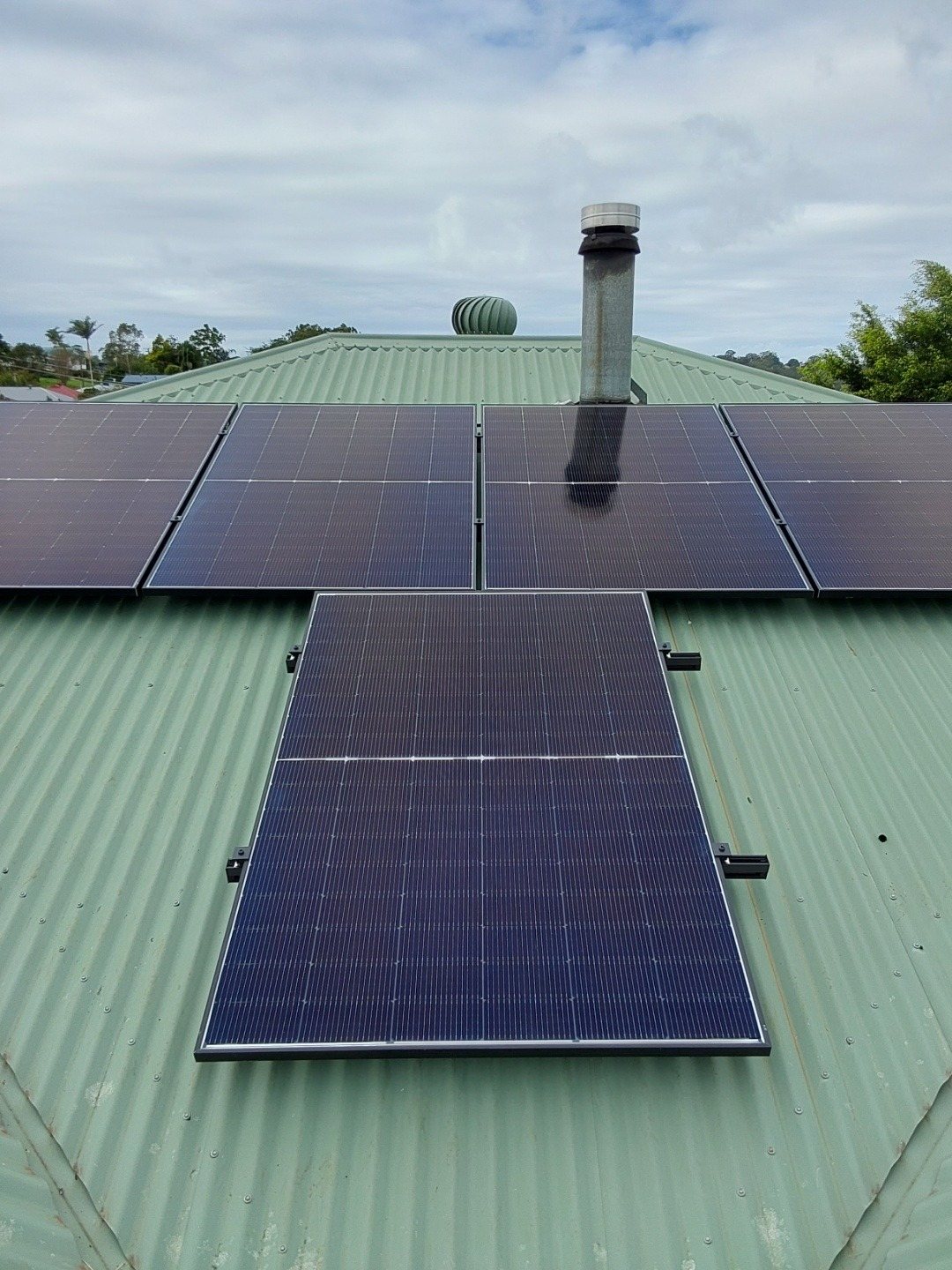 Jinko solar panels laid out around a flue on a green corrugated roof in East Lismore, installed by Sun Connect Solar