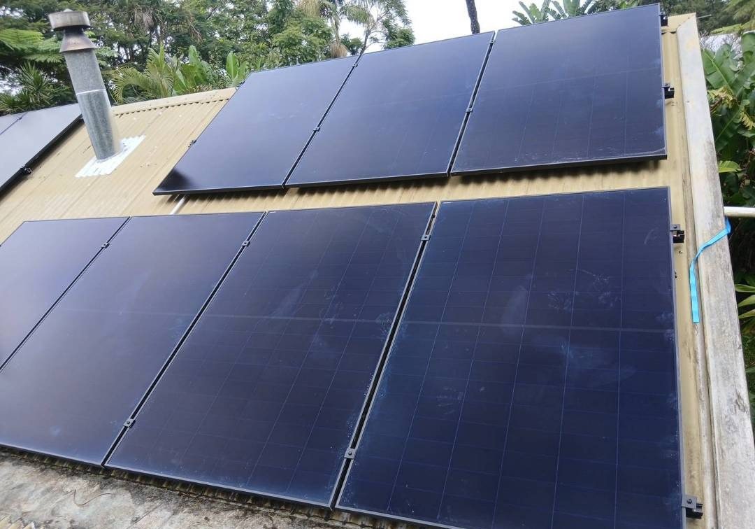 All-black AIKO solar panels in two rows on a corrugated roof beside a flue at Federal All-black AIKO solar panels in two rows on a corrugated roof beside a flue at Federal, part of a solar and 16 kWh Sigenergy battery install by Sun Connect Solar