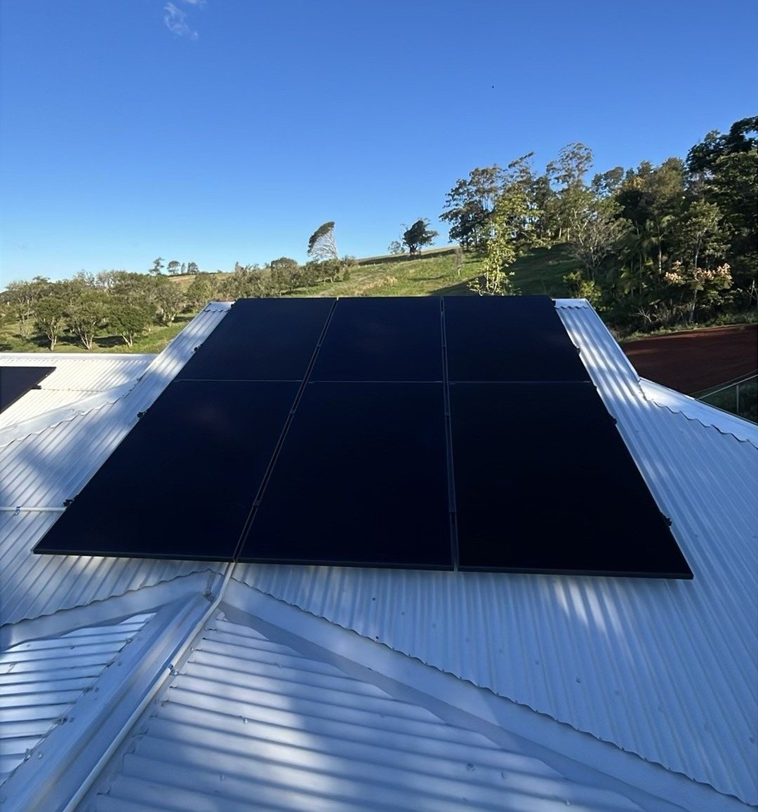 A block of all-black AIKO solar panels on a metal roof with the hills around Federal behind A block of all-black AIKO solar panels on a metal roof with the hills around Federal behind, installed by Sun Connect Solar