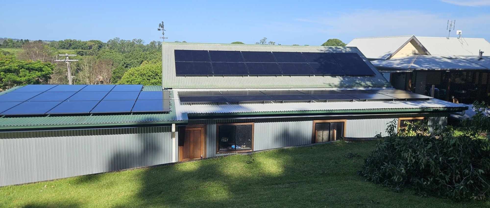 All-black AIKO solar panels on the roofs of a rural home and shed at Federal All-black AIKO solar panels on the roofs of a rural home and shed at Federal, with farmland behind, installed by Sun Connect Solar