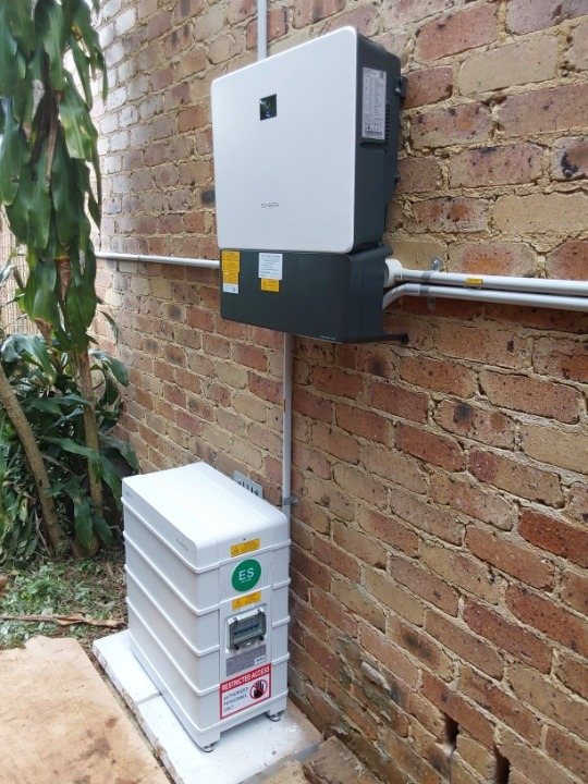 Sungrow SH10RS hybrid inverter on an old brick wall above a Sungrow SBR battery on cement pavers at Federal Sungrow SH10RS hybrid inverter on an old brick wall above a Sungrow SBR battery on cement pavers at Federal, installed by Sun Connect Solar