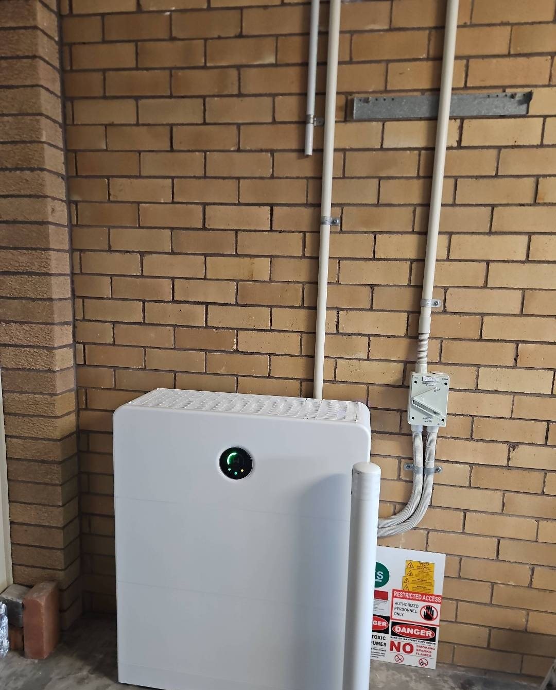 GoodWe ESA all-in-one battery and inverter GoodWe ESA all-in-one battery and inverter, 16.6 kWh, against a cream brick wall with a protective bollard in Goonellabah, installed by Sun Connect Solar