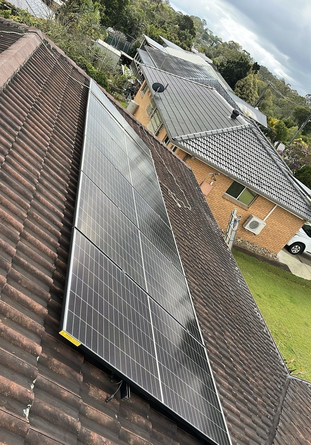 A long run of Jinko solar panels on a tiled roof among brick homes in Goonellabah A long run of Jinko solar panels on a tiled roof among brick homes in Goonellabah, installed by Sun Connect Solar