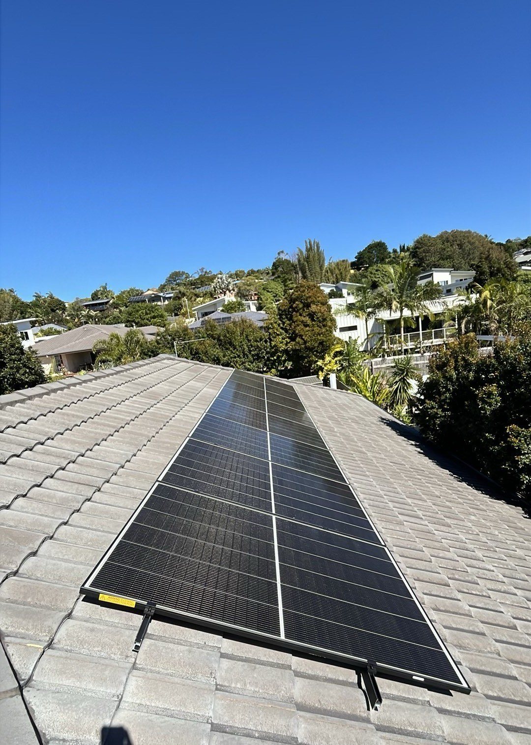 Jinko solar array on a pale tiled roof with green trees behind in Lennox Head Jinko solar array on a pale tiled roof with green trees behind in Lennox Head, installed by Sun Connect Solar