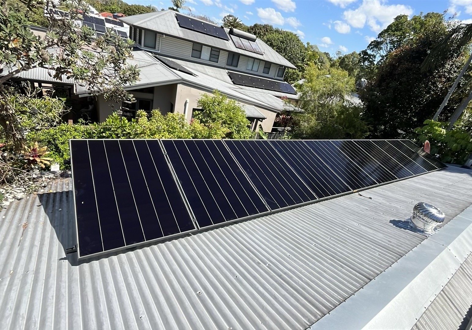 A long row of AIKO Neostar solar panels on a metal roof above gardens and neighbouring homes in Mullumbimby A long row of AIKO Neostar solar panels on a metal roof above gardens and neighbouring homes in Mullumbimby, part of a 12.25 kW install by Sun Connect Solar