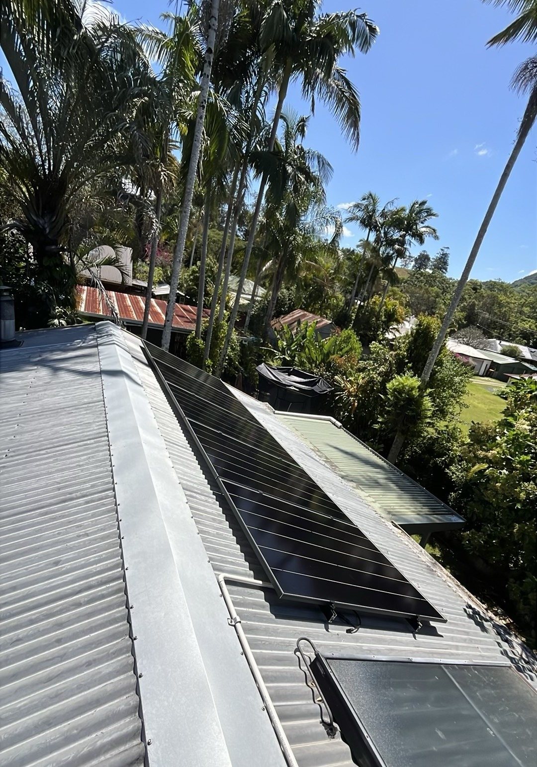 AIKO solar panels on tilt frames on a metal roof among palms in Mullumbimby AIKO solar panels on tilt frames on a metal roof among palms in Mullumbimby, installed by Sun Connect Solar