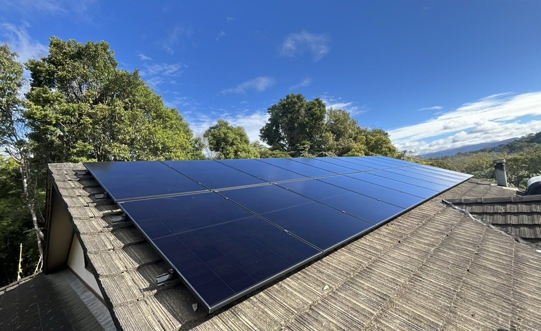 Rows of all-black AIKO solar panels on a dark tile roof with a view over the hinterland valley near Mullumbimby, part of a 27.4 kW solar and 50 kWh Sigenergy battery install by Sun Connect Solar