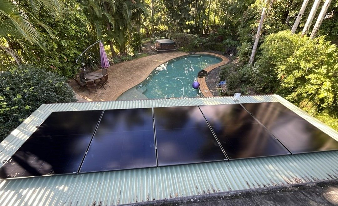All-black AIKO solar panels on a low roof above a pool and garden in the Mullumbimby hinterland, installed by Sun Connect Solar