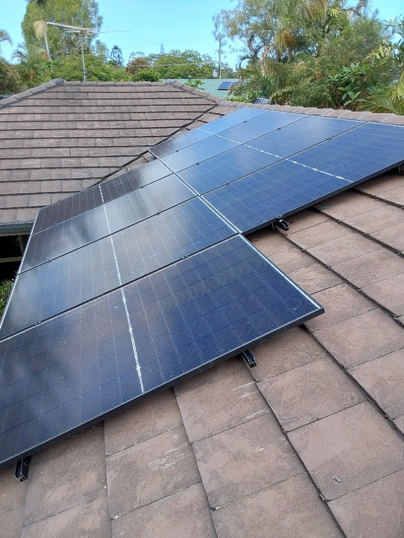 All-black Jinko solar panels on a brown tile roof among palms in Mullumbimby, part of an AlphaESS battery install by Sun Connect Solar