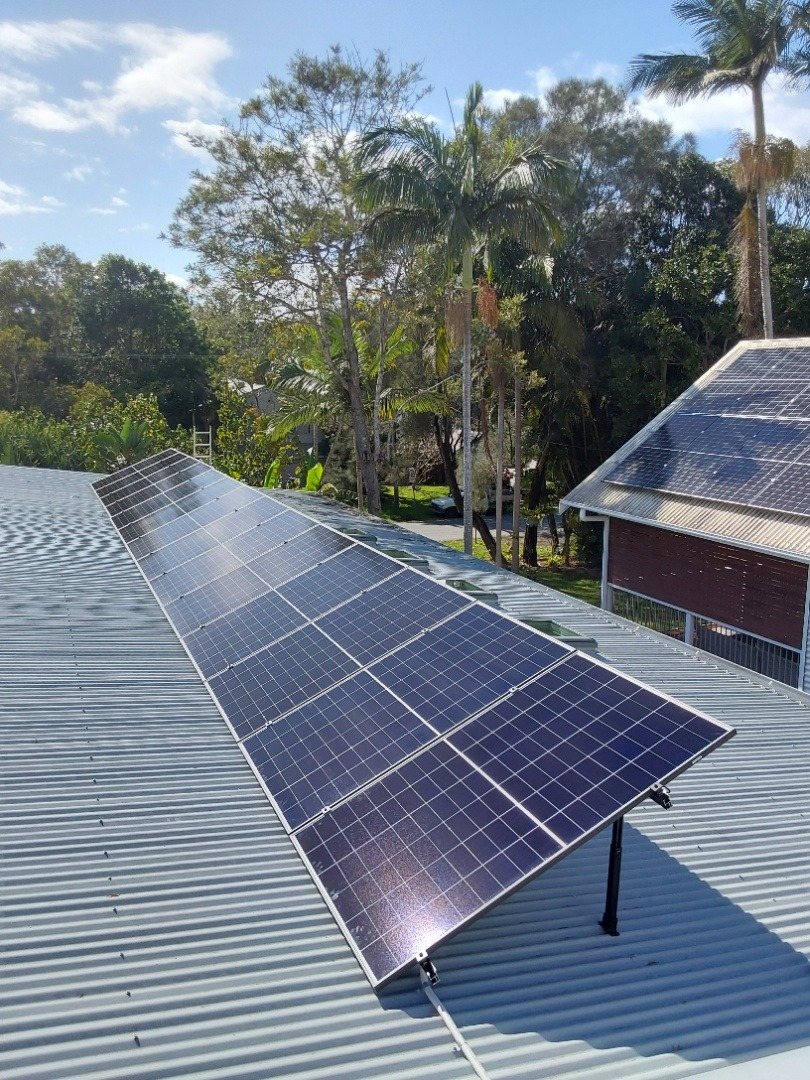 AIKO solar panels on adjustable tilt frames on a metal roof among palms at New Brighton AIKO solar panels on adjustable tilt frames on a metal roof among palms at New Brighton, installed by Sun Connect Solar