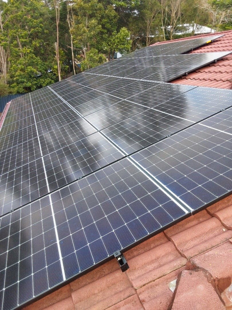 Rows of Jinko Tiger Neo solar panels on black anodised mounting rails on a terracotta tile roof in Ocean Shores, installed by Sun Connect Solar