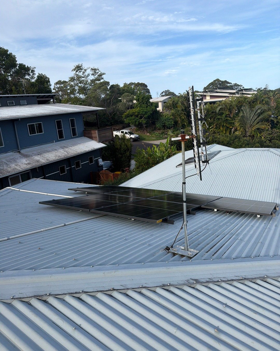 Jinko solar panels on a metal roof with hillside homes behind in Ocean Shores, installed by Sun Connect Solar