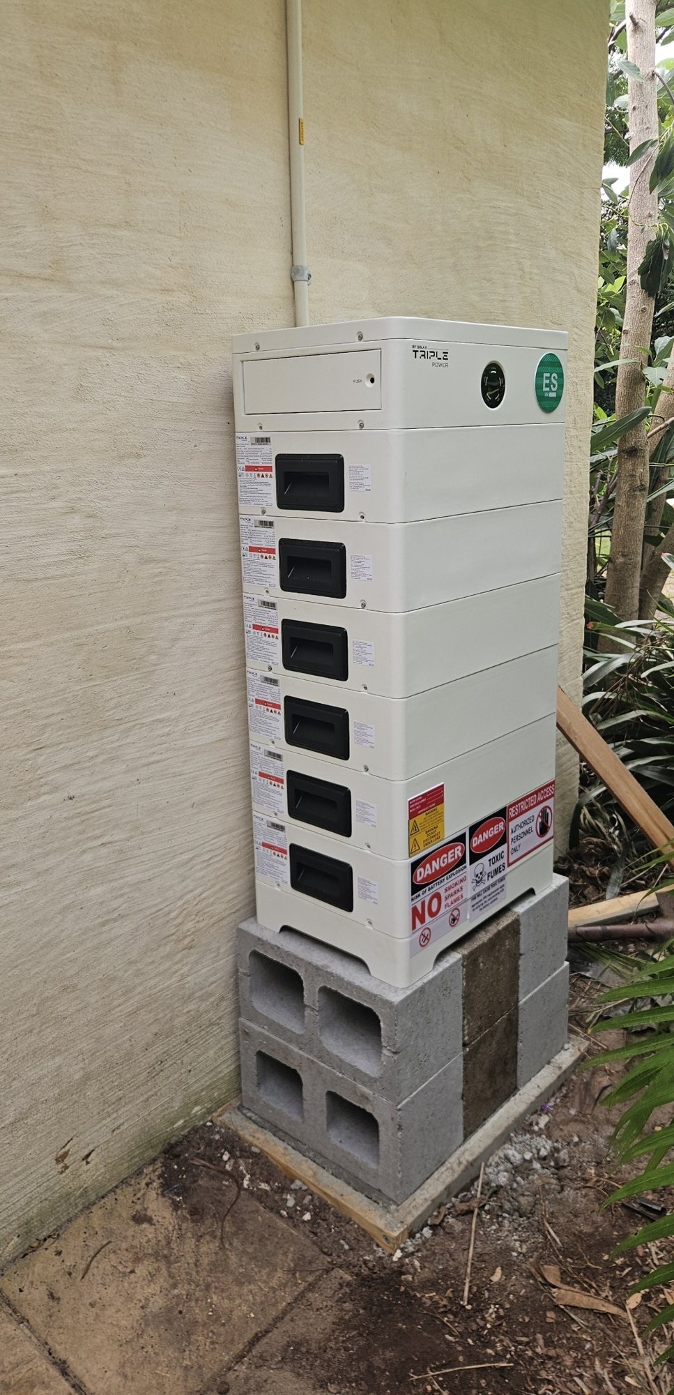 SolaX T-BAT battery stack of about 21.6 kWh standing on a besser block base against a rendered wall in Ocean Shores SolaX T-BAT battery stack of about 21.6 kWh standing on a besser block base against a rendered wall in Ocean Shores, installed by Sun Connect Solar