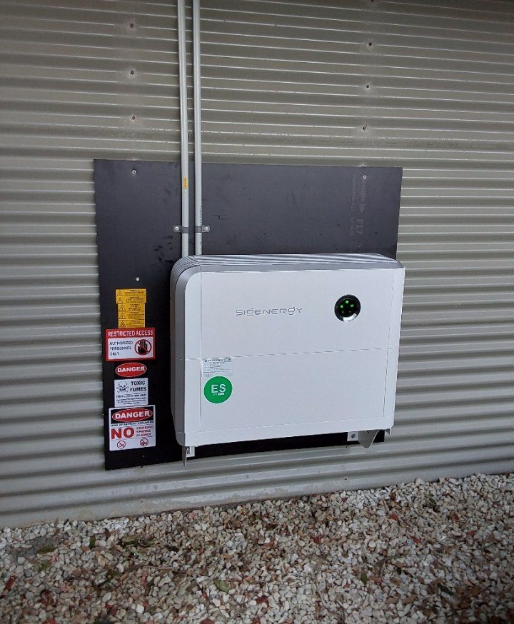 Wall-mounted Sigenergy 8 kWh battery and hybrid inverter on a backing board on a Colorbond-clad wall in Pottsville Wall-mounted Sigenergy 8 kWh battery and hybrid inverter on a backing board on a Colorbond-clad wall in Pottsville, installed by Sun Connect Solar