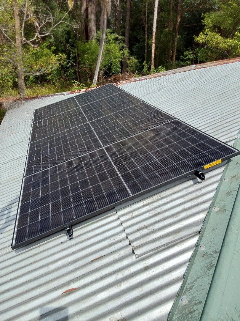 Jinko Tiger Neo solar panels on a galvanised corrugated roof with tall forest behind at Rosebank Jinko Tiger Neo solar panels on a galvanised corrugated roof with tall forest behind at Rosebank, installed by Sun Connect Solar
