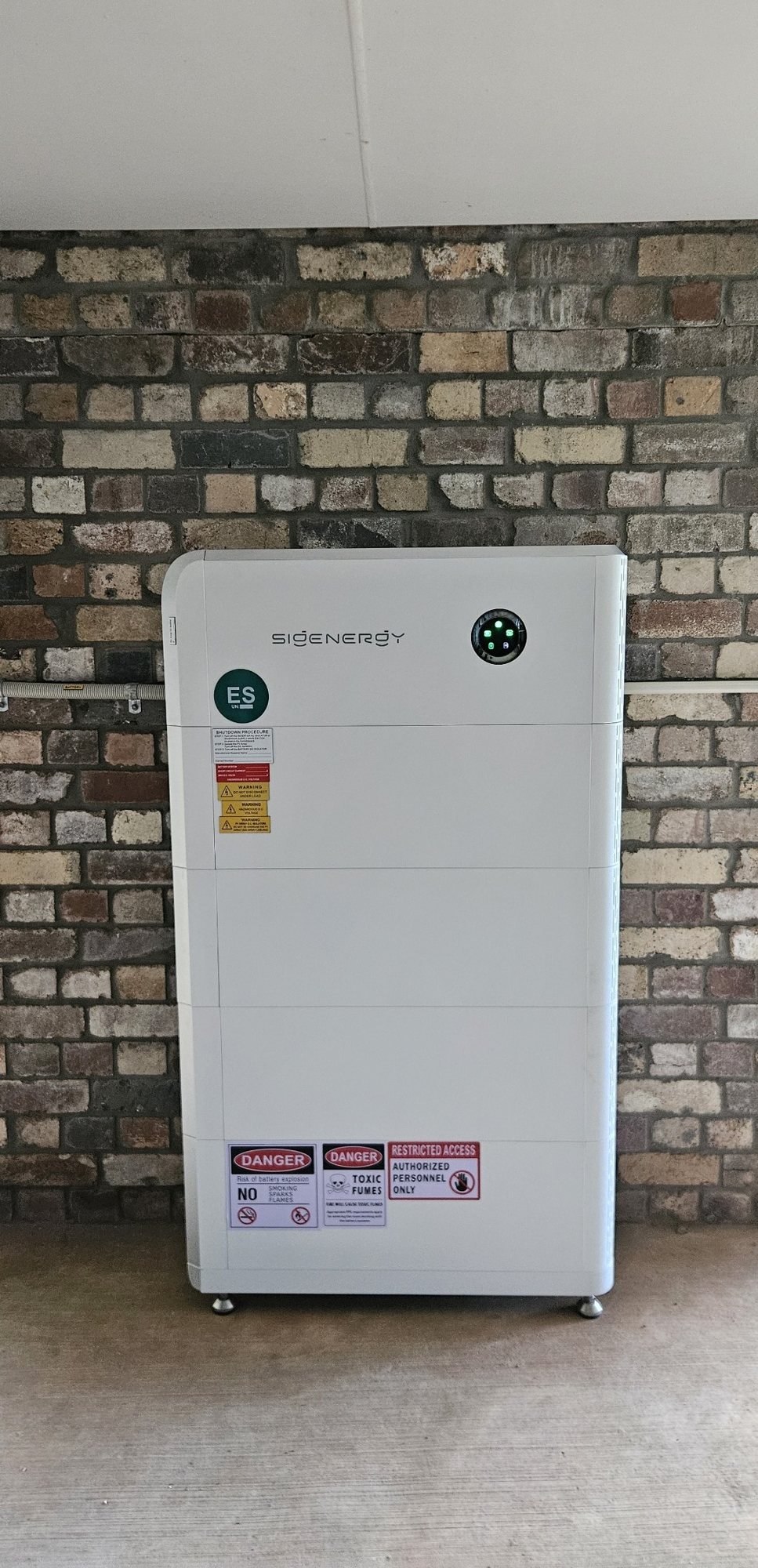 Sigenergy SigenStor battery with four modules Sigenergy SigenStor battery with four modules, about 32 kWh, against an old brick wall under cover at Rosebank, installed by Sun Connect Solar