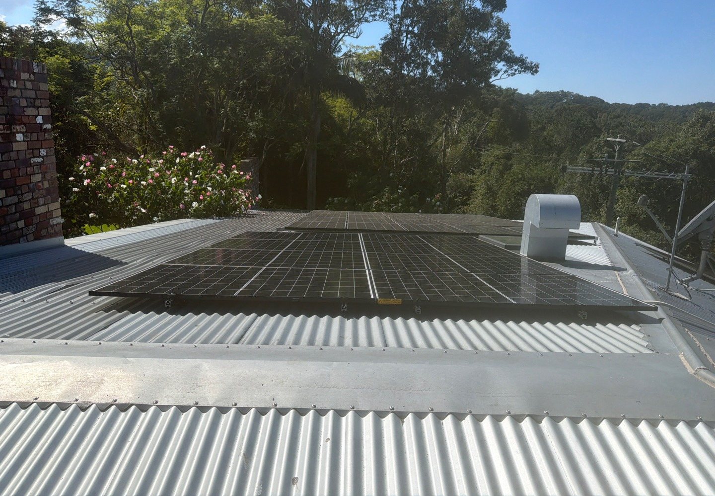 Trina solar panels on a low-pitched metal roof with a garden and the hills around Rosebank behind Trina solar panels on a low-pitched metal roof with a garden and the hills around Rosebank behind, installed by Sun Connect Solar