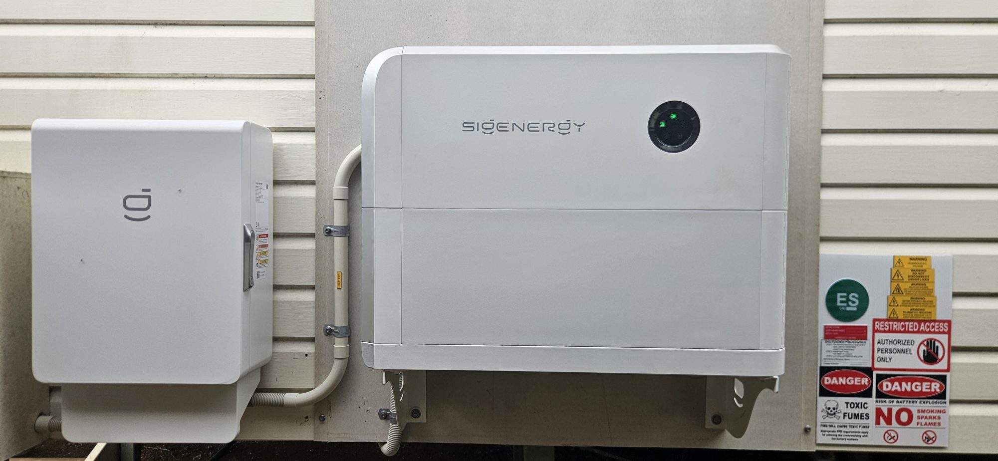 Sigenergy SigenStor home battery mounted on an outside wall with warning signage, Lismore area install by Sun Connect Solar