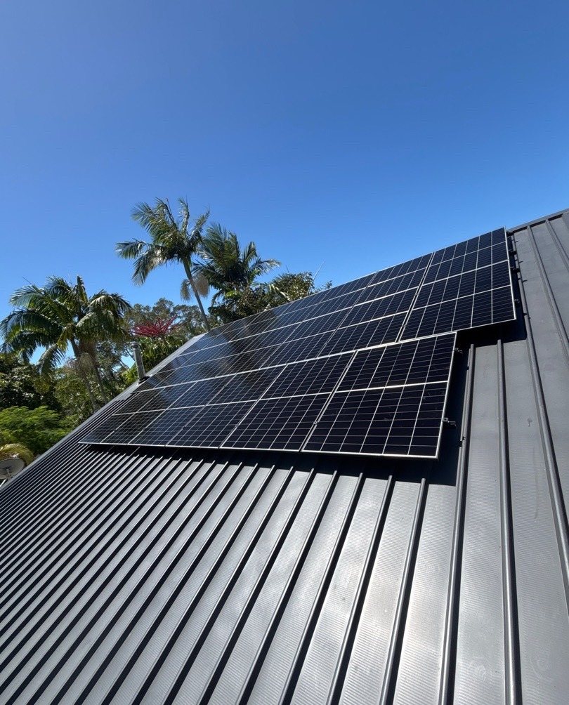 AIKO solar panels on a grey Colorbond roof among palms in South Golden Beach, part of a 14.1 kW solar and Sigenergy battery install by Sun Connect Solar