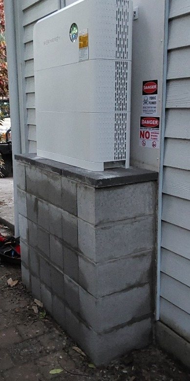 Sigenergy 16 kWh battery and hybrid inverter on a raised block base against a weatherboard wall in South Golden Beach, installed by Sun Connect Solar