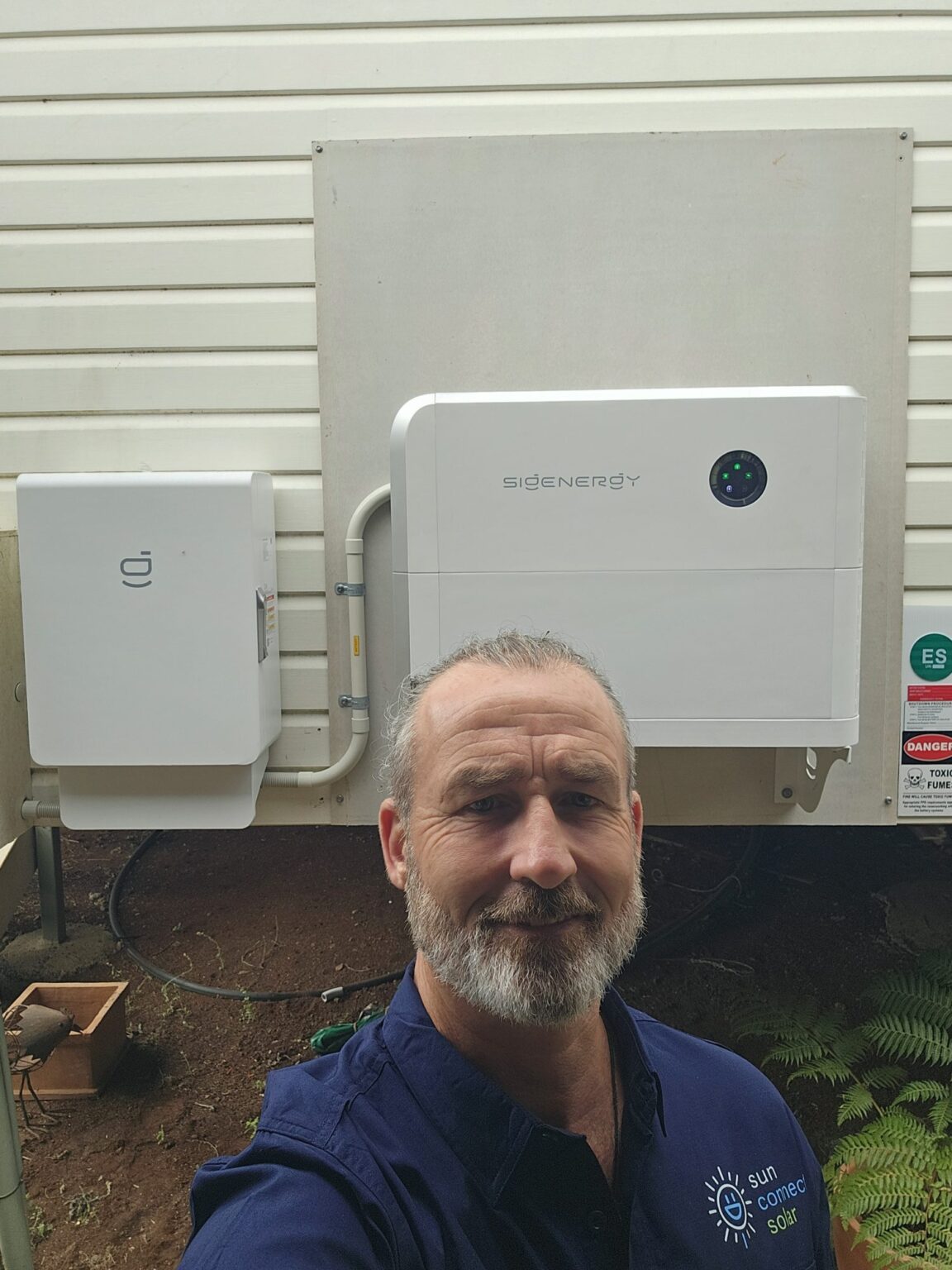 Sun Connect Solar electrician in front of a finished Sigenergy battery installation near Lismore