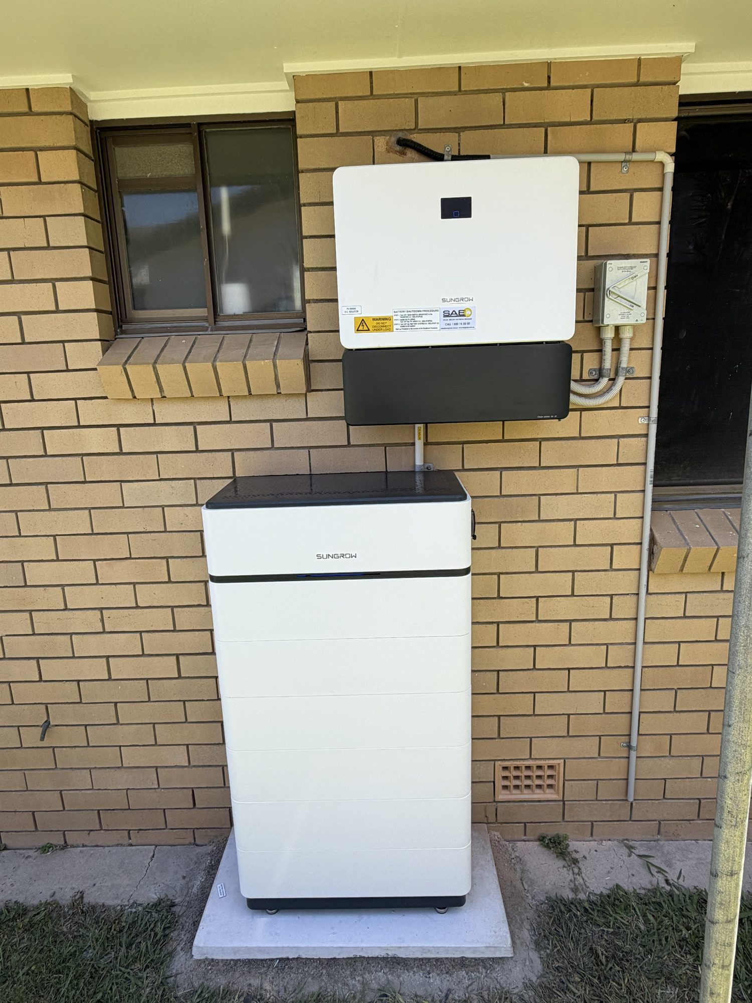 Sungrow hybrid inverter above a Sungrow battery stack on a brick wall, installed by Sun Connect Solar in the Northern Rivers