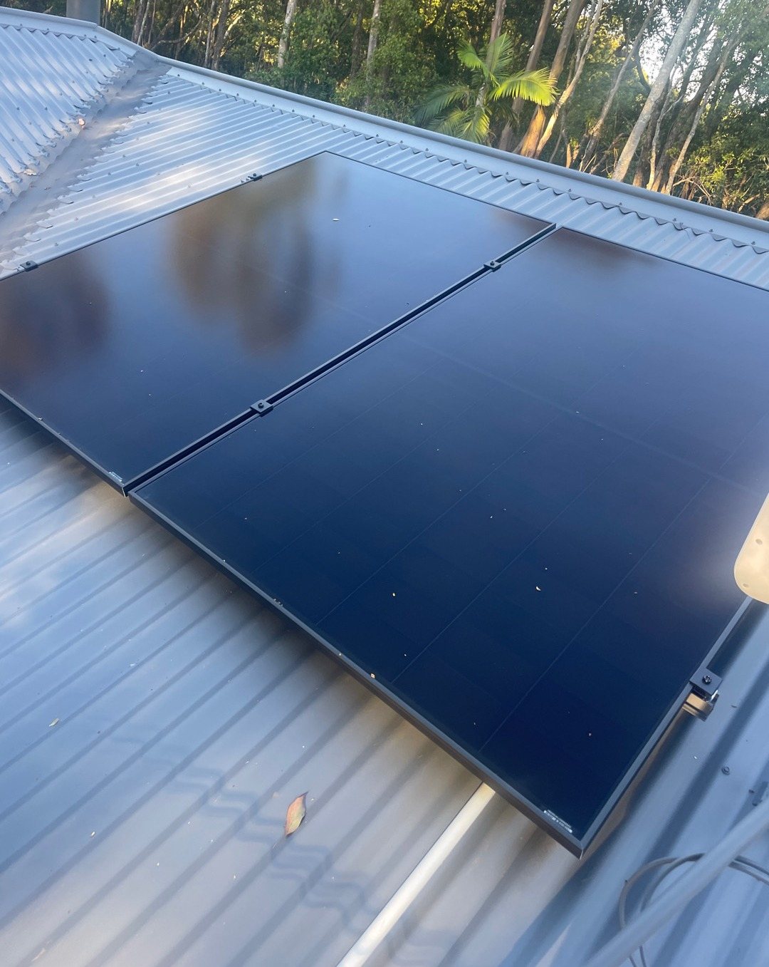 Close view of all-black AIKO solar panels on a grey metal roof at The Pocket, installed by Sun Connect Solar