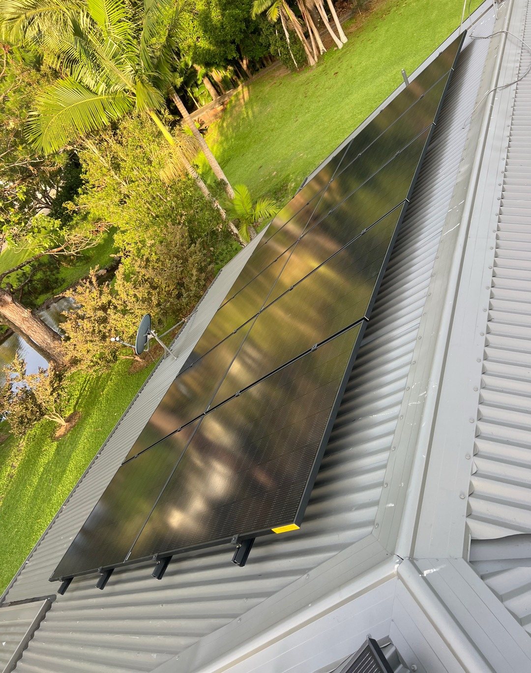 A row of all-black Jinko solar panels along a corrugated roof above a garden near Murwillumbah A row of all-black Jinko solar panels along a corrugated roof above a garden near Murwillumbah, installed by Sun Connect Solar