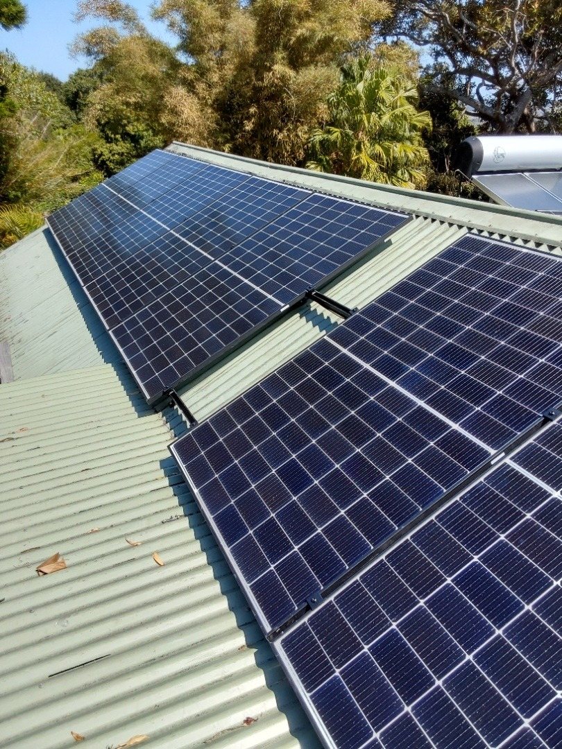 Two blocks of Seraphim solar panels on a green metal roof among trees at Tyagarah Two blocks of Seraphim solar panels on a green metal roof among trees at Tyagarah, installed by Sun Connect Solar