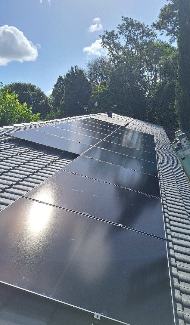 AIKO solar array along a tiled roof with tall trees behind in Wollongbar AIKO solar array along a tiled roof with tall trees behind in Wollongbar, installed by Sun Connect Solar